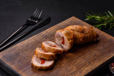 Lezzetli fırınlanmış et rulosu tavuk eti, baharatlı tatlı biber ve ahşap kesme tahtasındaki otlar.