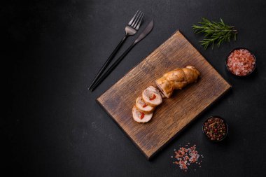 Lezzetli fırınlanmış et rulosu tavuk eti, baharatlı tatlı biber ve ahşap kesme tahtasındaki otlar.