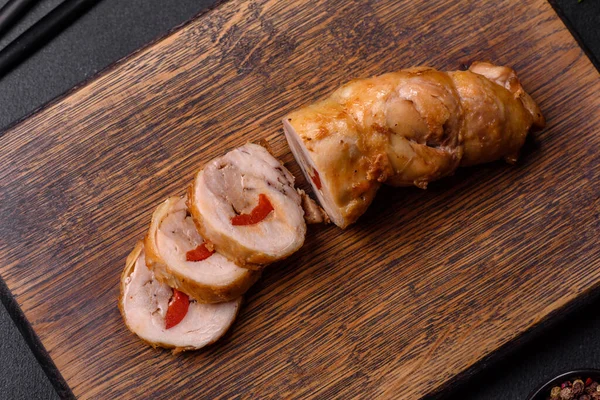Tasty baked meat roll of chicken meat, sweet pepper with spices and herbs on a wooden cutting board