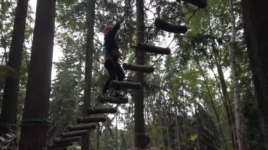 7 yaşındaki çocuk orman ormanlarındaki parkta ağaçlara tırmanıyor ve Albavilla Italya 'daki doğada maceraya atılmak için miğfer ve koşum takımlarıyla ipler üzerinde zorlu denge testlerinden geçiyor. 