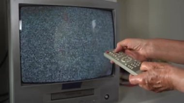 Televizyonda uzaktan kumandalı yaşlı kadın. 