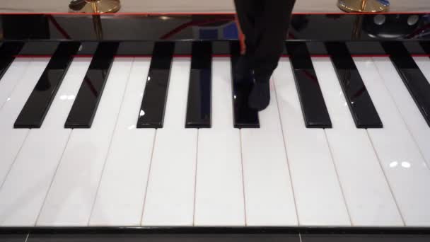 あなたの足でピアノを演奏 足は音楽ノートを演奏するマキシピアノのヘッドボードの鍵で実行されます — ストック動画