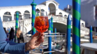 Kız el ele tutuşup aşk şehrinde bir bardak Spritz içiyor - aperatif, alkollü içecek Spritz Camapari ya da Aperol - Venedik 'in tipik içeceği beyaz şaraptan, portakallı - Rialto Köprüsü 