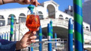 Kız el ele tutuşup aşk şehrinde bir bardak Spritz içiyor - aperatif, alkollü içecek Spritz Camapari ya da Aperol - Venedik 'in tipik içeceği beyaz şaraptan, portakallı - Rialto Köprüsü 