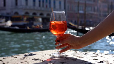 Kız el ele tutuşup aşk şehrinde bir bardak Spritz içiyor - aperatif, alkollü içecek Spritz Camapari ya da Aperol - Venedik 'in tipik içeceği beyaz şaraptan, portakallı - Rialto Köprüsü 