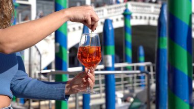 Kız el ele tutuşup aşk şehrinde bir bardak Spritz içiyor - aperatif, alkollü içecek Spritz Camapari ya da Aperol - Venedik 'in tipik içeceği beyaz şaraptan, portakallı - Rialto Köprüsü 