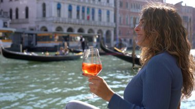 Kız el ele tutuşup aşk şehrinde bir bardak Spritz içiyor - aperatif, alkollü içecek Spritz Camapari ya da Aperol - Venedik 'in tipik içeceği beyaz şaraptan, portakallı - Rialto Köprüsü 
