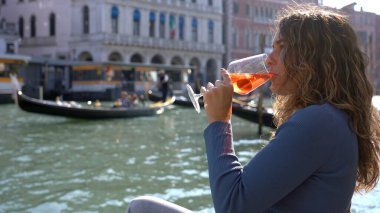 Kız el ele tutuşup aşk şehrinde bir bardak Spritz içiyor - aperatif, alkollü içecek Spritz Camapari ya da Aperol - Venedik 'in tipik içeceği beyaz şaraptan, portakallı - Rialto Köprüsü 