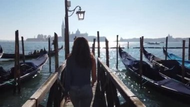 Avrupa, İtalya Kasım 2021 - Venedik gölündeki gondol teknelerinin ahşap güvertesinde yürüyen kız - İtalya 'daki Covid-19 Coronavirus' un sona ermesiyle turizm devam ediyor - Murano