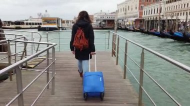 Avrupa, İtalya Kasım 2021. Tramvay valizli kadın, turist, Büyük Kanal Venedik 'teki aşk şehrinde feribot bekliyor. Covid-19 Coronavirus salgını sırasında seyahat ediyorlar.