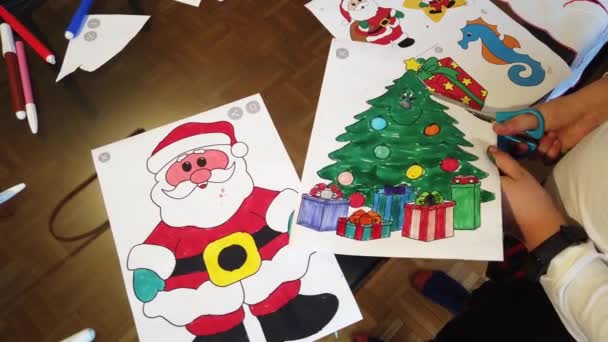 男孩用剪子剪下圣诞彩页 用圣诞老人和圣诞树剪下 — 图库视频影像