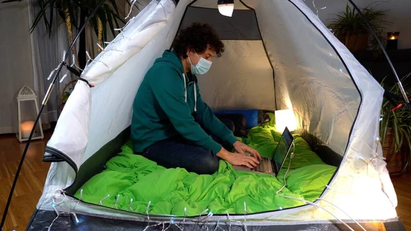 Father watching the computer laptop in a tent camping home during Covid-19 Coronavirus lockdown - Smart working and lifestyle in apartment during epidemic