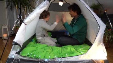 Avrupa, İtalya, Milano - Covid-19 Coronavirus tecridi sırasında evde baba ve oğul bir çadırda el ele oynayarak kamp kurdular.