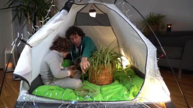 Avrupa, İtalya, Milano - Covid-19 Coronavirus tecridi sırasında evde baba ve oğul bir çadırda el ele oynayarak kamp kurdular.