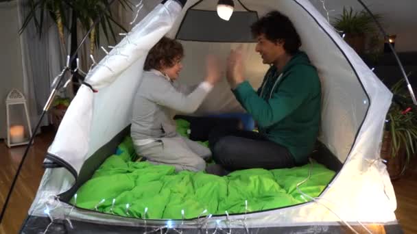 ヨーロッパ イタリア ミラノ Covid 19の間に自宅で父と息子の子供コロナウイルスのロックダウンアパートのテントで手で遊んで 家にキャンプ — ストック動画