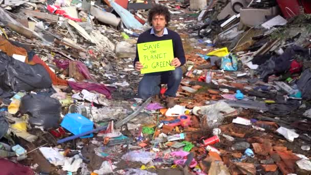地球を救うという言葉で看板を掲げる40歳の生態学者は ゴミ捨て場の廃棄物の中で気候変動 地球温暖化 大気汚染に抗議し 緑になる — ストック動画