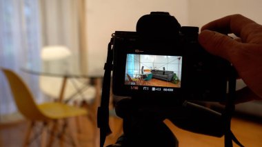 photo of professional photographer filming new flat on digital devices and video camera on the tripod. focus in background
