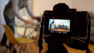 photo of professional photographer filming new flat on digital devices and video camera on the tripod. focus in background