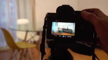 photo of professional photographer filming new flat on digital devices and video camera on the tripod. focus in background