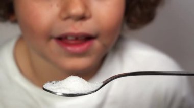 Bir kaşık dolusu şeker ve çocuğun yakın çekim görüntüleri tadını alıyor.