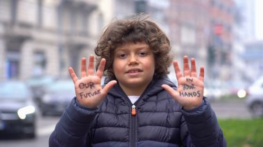Yedi yaşında, elleri havada ve avuçlarında yazılı bir çocuk. Geleceğimiz bizim ellerimizde. Gezegenimizi kurtarın. Dünyamız senin ellerinde. Dünyayı kurtarma kampanyası için tasarım kavramı, sürdürülebilir çevre ve iklim değişikliği dünyanın geleceğidir..