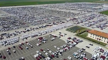 Otoparka park edilmiş yeni arabaların hava görüntüleri. Araba satıcısı otoparkı yeni otomobillerle dolu. Yeni arabalar ithalat ve ihracat için dizildi - yeşil devrim ve elektrikli araba yakıt ve benzin yok