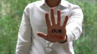 Man with writing on hands, in our hands is Future lettering, Self-esteem, and confidence in the future in a time of economic crisis war, and climate change, Set goals and achieve them with your skills.   