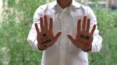 Man with writing on hands, in our hands is Future lettering, Self-esteem, and confidence in the future in a time of economic crisis war, and climate change, Set goals and achieve them with your skills.   