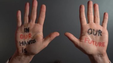Man with writing on hands, in our hands is Future lettering, Self-esteem, and confidence in the future in a time of economic crisis war, and climate change, Set goals and achieve them with your skills.  