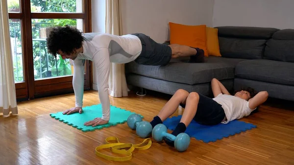 father and 7-year-old son boy do gym gymnastics at home with the arrival of spring they get ready for summer, push-ups, and abdominals - sports activities indoor