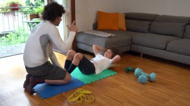 Baba ve 7 yaşındaki oğlu baharın gelmesiyle birlikte evde jimnastik yapıyor yaz için hazırlanıyorlar, şınav ve karın aktiviteleri - kapalı alandaki spor aktiviteleri
