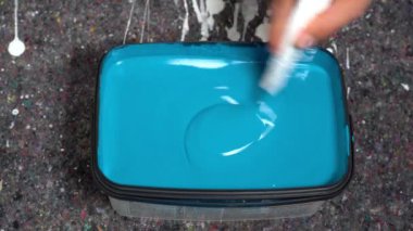 Mavi boya ve fırçalı plastik bir konteynırın yakın çekim görüntüleri.