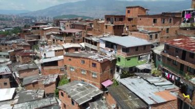 Medellin, Kolombiya, Comuna 13 gecekondu bölgesinin insansız hava aracı görüntüsü. Bir zamanlar dünyanın en tehlikeli mahallelerinden biri olan Favela evleri ve şehir merkezindeki modern gökyüzü.