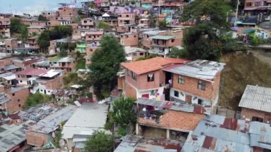 Medellin, Kolombiya, Comuna 13 gecekondu bölgesinin insansız hava aracı görüntüsü. Bir zamanlar dünyanın en tehlikeli mahallelerinden biri olan Favela evleri ve şehir merkezindeki modern gökyüzü.