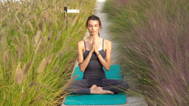 Spor kıyafetli genç bir kız, Milan şehir merkezindeki bahçe evinin ortak alanlarında yoga meditasyon egzersizleri yapıyor. Spor ve fiziksel refah.