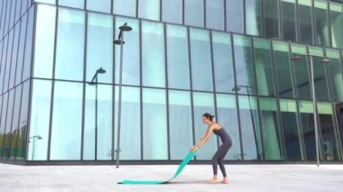 21 yaşındaki kız, modern şehir merkezindeki gökdelenlerin yakınında yoga jimnastik yapıyor. Milano şehrinde rahatlama ve meditasyon. Şehir hayatının koşuşturması ve çabasıyla fiziksel ve zihinsel egzersizlerle mücadele ediyor.  