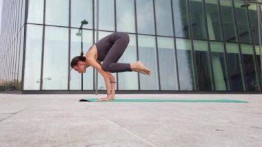 21 yaşındaki kız, modern şehir merkezindeki gökdelenlerin yakınında yoga jimnastik yapıyor. Milano şehrinde rahatlama ve meditasyon. Şehir hayatının koşuşturması ve çabasıyla fiziksel ve zihinsel egzersizlerle mücadele ediyor.