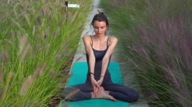 21 yaşındaki kız, doğal botanik bahçesinde yoga jimnastik yapıyor. Milano şehrinde rahatlama ve meditasyon. Şehir yaşamının çabukluğu ve çabasıyla fiziksel ve zihinsel egzersizlerle mücadele ediyor.