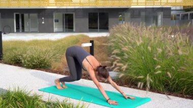 Spor kıyafetli genç bir kız, Milan şehir merkezindeki bahçe evinin ortak alanlarında yoga meditasyon egzersizleri yapıyor. Spor ve fiziksel refah.