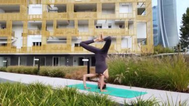 Spor kıyafetli genç bir kız, Milan şehir merkezindeki bahçe evinin ortak alanlarında yoga meditasyon egzersizleri yapıyor. Spor ve fiziksel refah.