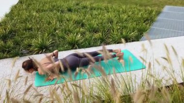 Spor kıyafetli genç bir kız, Milan şehir merkezindeki bahçe evinin ortak alanlarında yoga meditasyon egzersizleri yapıyor. Spor ve fiziksel refah.
