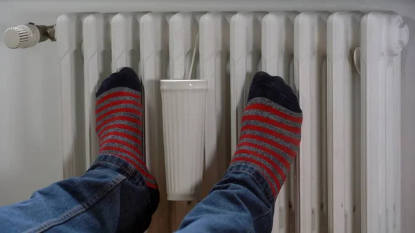 increase in the cost of gas and heating problems in homes due to the energy crisis - a boy at home near the heater to heat suffers from the cold