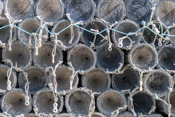 A stack of cylindrical crab or lobster traps stored on a jetty at Aberystwyth harbour. The traps are seen end on creating a pattern of circles and ropes