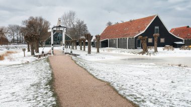 Eski bir Hollanda köyünde küçük asma köprü ve ahşap evler.
