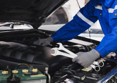 Tamirci garajdaki arabanın motoru üzerinde çalışıyor. Araba teftiş hizmeti ve araba tamir hizmeti kavramı..