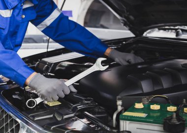 Tamirci garajdaki arabanın motoru üzerinde çalışıyor. Araba teftiş hizmeti ve araba tamir hizmeti kavramı..