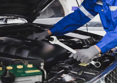 Tamirci garajdaki arabanın motoru üzerinde çalışıyor. Araba teftiş hizmeti ve araba tamir hizmeti kavramı..