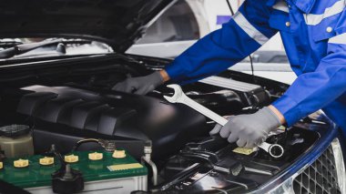 Tamirci garajdaki arabanın motoru üzerinde çalışıyor. Araba teftiş hizmeti ve araba tamir hizmeti kavramı..