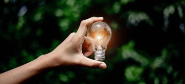 El ele tutuşmak ampul, doğal enerji ve dünya konseptini sevmek.