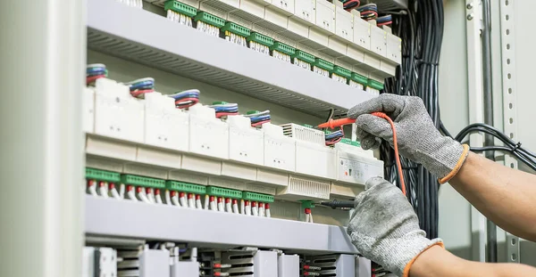 Electrical engineer tests the operation of the electric control cabinet on a regular basis for maintenance.